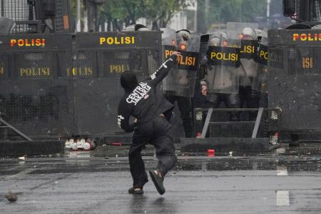 ３１日、インドネシア・ジャカルタの議会付近で警官隊に石を投げつけるデモ参加者（ＡＰ＝共同）