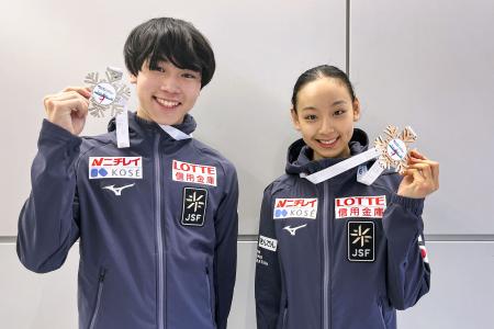 ジュニアＧＰシリーズ第２戦トルコ大会で獲得したメダルを掲げる女子優勝の岡万佑子（右）と男子２位の高橋星名＝１日、成田空港