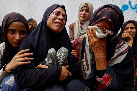 イスラエル軍の攻撃により犠牲になった息子の靴を抱え、死を悼む母親ら＝８月、ガザ北部ガザ市（ロイター＝共同）
