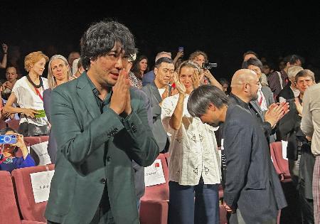 ベネチア国際映画祭で「ＬＯＳＴ　ＬＡＮＤ／ロストランド」の公式上映後、観客の拍手に応える藤元明緒監督（手前）＝１日、イタリア・ベネチア（共同）