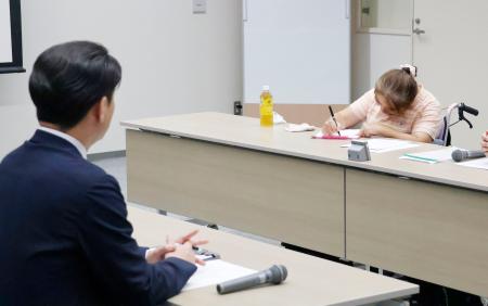 トライグループの現地研修で「子どもたちに正確に伝えてほしい」と筆談で訴えた、胎児性水俣病患者の古山知恵子さん。手前は阿部正純執行役員＝２日午後、新潟市