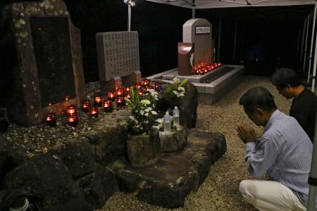 紀伊半島豪雨から１４年となり、慰霊碑前で手を合わせる遺族ら＝４日未明、和歌山県那智勝浦町