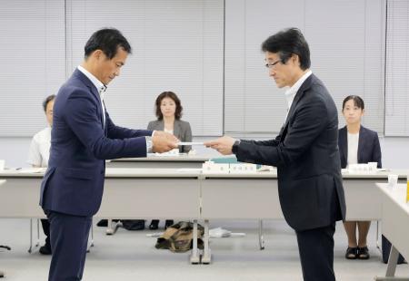 大分労働局長（左）に答申する大分地方最低賃金審議会の井田雅貴会長＝４日午後、大分市