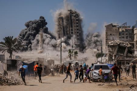 ５日、イスラエル軍の攻撃で高層ビルが崩壊し、逃げる人々＝パレスチナ自治区ガザ市（ＡＰ＝共同）