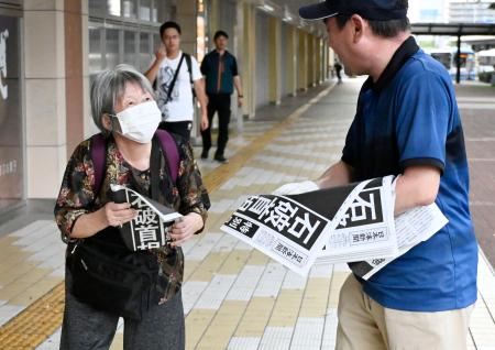 石破首相が辞任の意向を固めたことを伝える号外を受け取る女性＝７日午後５時１９分、ＪＲ鳥取駅前