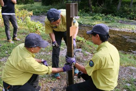 ヒグマ撮影者らの滞留が目立つイワウベツ川付近に監視カメラを設置する環境省職員＝１２日午後、北海道斜里町