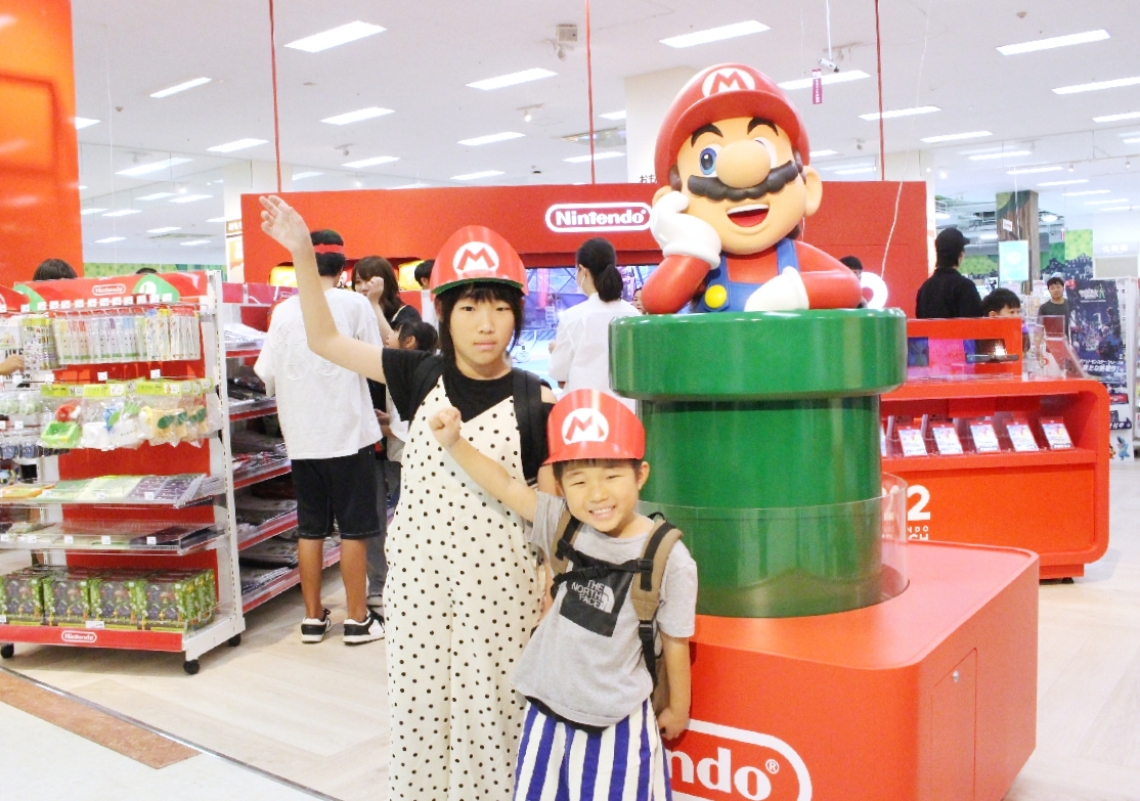 マリオのモニュメントと記念撮影する子どもたち＝１３日、大分市