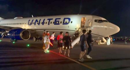 関西空港に緊急着陸したユナイテッド航空機から、脱出用シューターを使って避難する乗客ら＝１２日夜（乗客提供）
