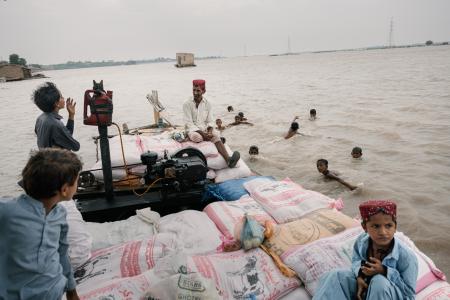 パキスタン南部で水量の増えたインダス川を渡る人々＝２０２４年８月（ゲッティ＝共同）