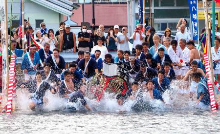 「海中みそぎ」でみこしと海へ飛び込む担ぎ手たち＝２１日午後、和歌山県那智勝浦町