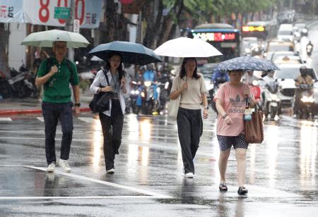 台風１８号の影響で雨が降る中、歩く人たち＝２３日、台北（ＡＰ＝共同）