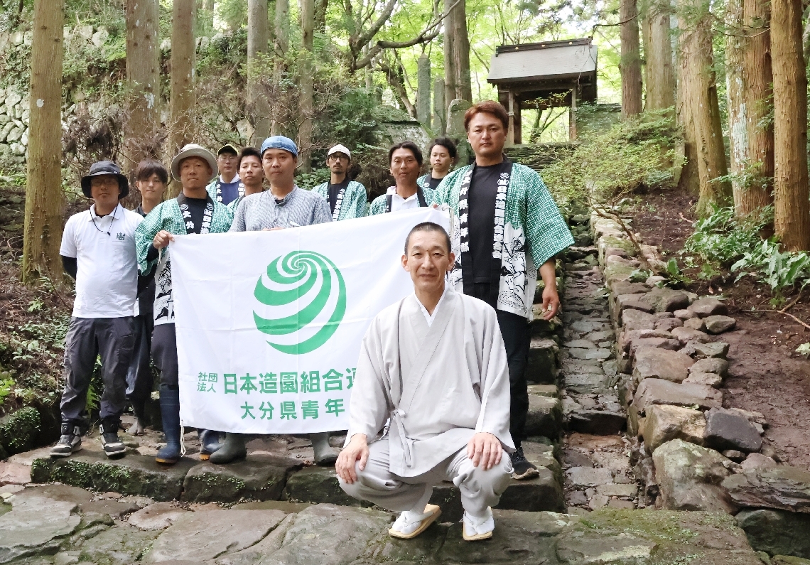 石積み水路（右）を修復した日本造園組合連合会県支部の青年部メンバーらと、寺田豪淳副住職（前列）＝国東市安岐町