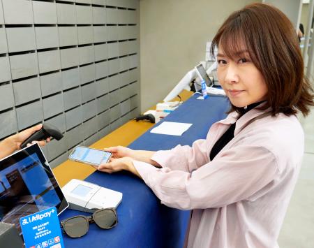 ２９日、ソウル・明洞にある人気のサングラス店で「海外支払いモード」の利用を実演するペイペイの担当者（画像の一部を加工しています、共同）