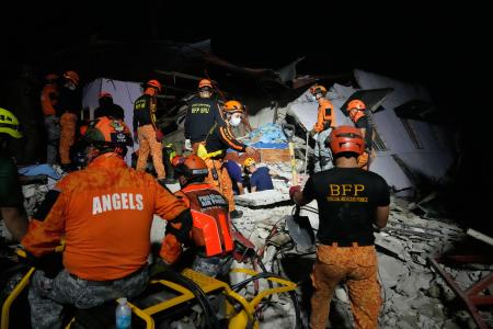 １日、フィリピン・セブ島のボゴで、倒壊した建物を調べる捜索隊員（ＡＰ＝共同）
