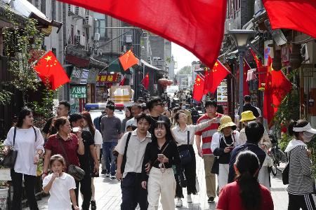 国慶節を迎え、中国国旗が掲げられた北京市内の観光地を歩く人たち＝１日