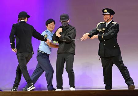 特殊詐欺の犯人役（左から３人目）をヨーヨーの糸を使って取り押さえるパフォーマーら＝５日午後、東京都昭島市