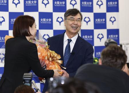 ノーベル生理学・医学賞の受賞が決まり、笑顔で花束を受け取る大阪大の坂口志文特任教授（右）＝６日午後８時３分、大阪府吹田市