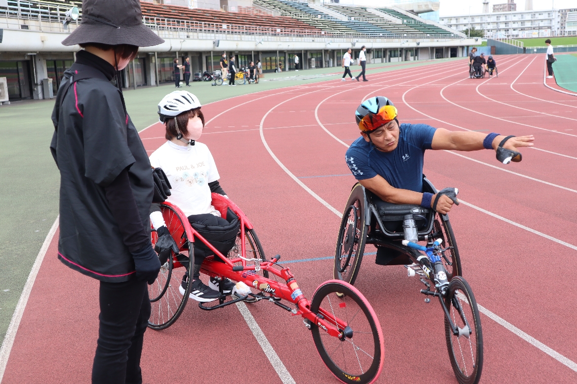 ベテラン選手（右）からアドバイスを受ける初挑戦の選手＝５日、大分市西浜
