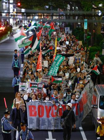 イスラエルとイスラム組織ハマスの戦闘開始から２年となり、パレスチナ自治区ガザでの戦闘中止を求めてデモ行進する人たち＝７日夜、東京・渋谷
