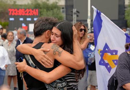９日、イスラエル中部テルアビブで、和平計画の「第１段階」合意の報道に抱き合って涙を流す女性（共同）