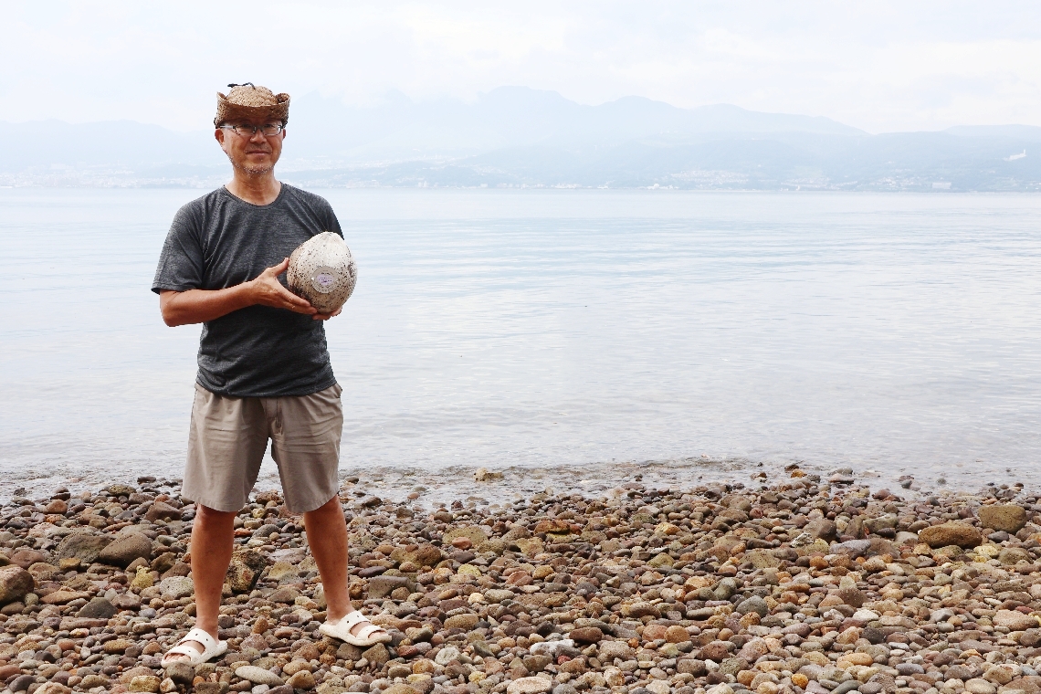ヤシの実を見つけた桜井高志さん＝日出町川崎