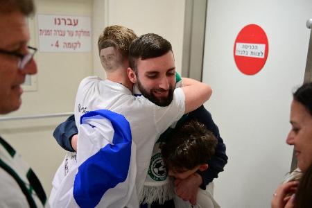 イスラム組織ハマスから解放され、抱き合うマタン・アングレストさん（中央右）＝１３日、イスラエル中部テルアビブ（ロイター＝共同）