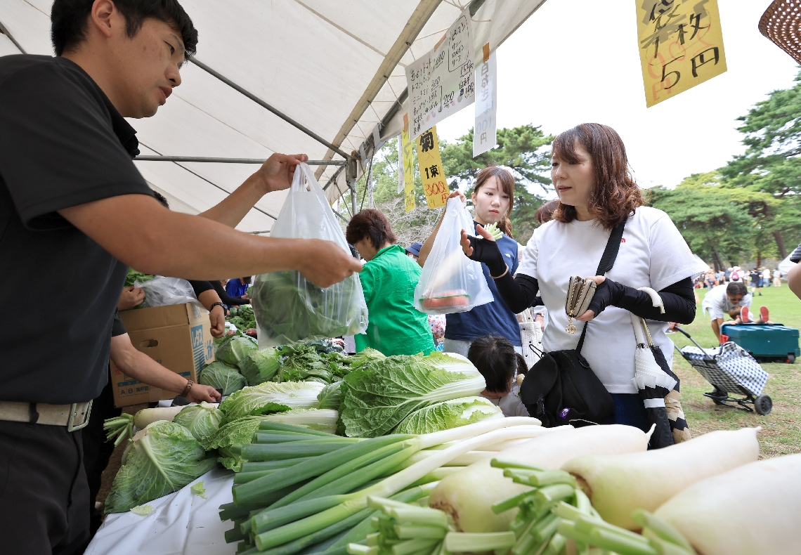 店頭に並んだ新鮮な野菜を買い求める来場者