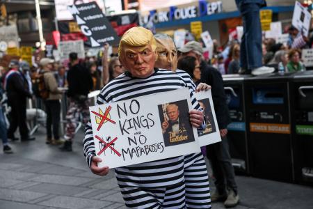 トランプ大統領の政治手法に抗議するデモで「ＮＯ　ＫＩＮＧＳ（王はいらない）」を掲げる参加者＝１８日、ニューヨーク（ロイター＝共同）