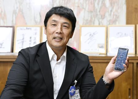自身のスマートフォンを手に、インタビューに答える愛知県豊明市の小浮正典市長＝９月、豊明市役所