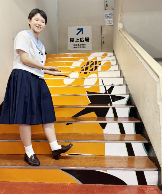 屋上広場へ続く階段に末永菜央さんが描いた作品「芽生えから空へ」