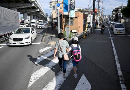 通学に同行し、支援するヘルパー（左）＝９月、大阪府豊中市