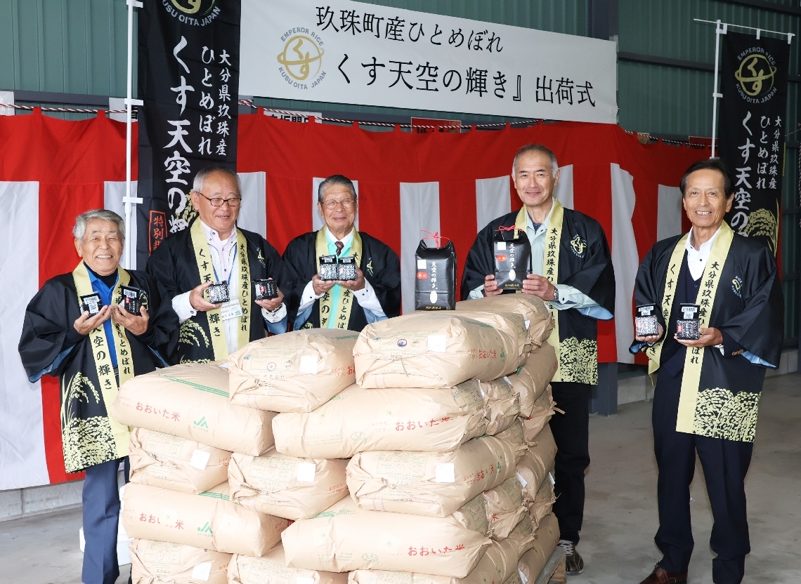 黒色を基調にした「くす天空の輝き」のパッケージを手に初出荷を喜ぶ生産者代表＝玖珠町帆足のくすここのえ産直ネット