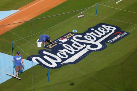 ドジャースの本拠地でワールドシリーズのロゴの作業をする人たち＝２６日、ロサンゼルス（ゲッティ＝共同）