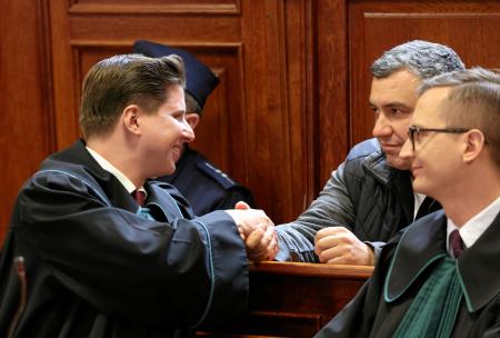 ドイツへの移送を認めない裁判所の判断を受け、弁護士と握手する「ノルドストリーム」破壊事件の容疑者（右奥）＝１７日、ワルシャワ（ロイター＝共同）