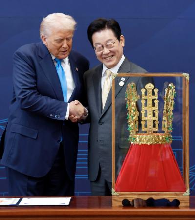 韓国・慶州で、トランプ米大統領（左）に「天馬塚金冠」のレプリカを贈呈し握手する李在明大統領＝２９日（聯合＝共同）