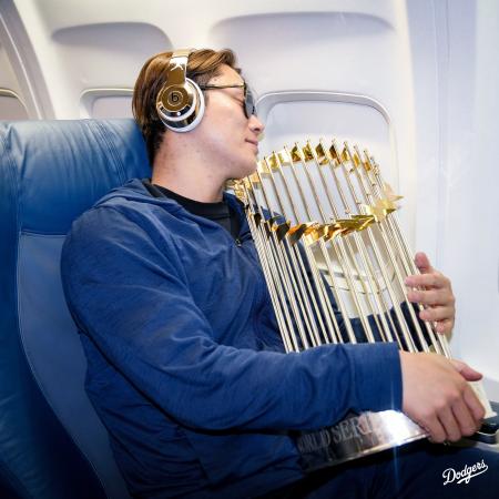 ロサンゼルスへ移動する機内で優勝トロフィーを抱きながら寝るような姿のドジャース・山本（ドジャースの球団公式Ｘから）