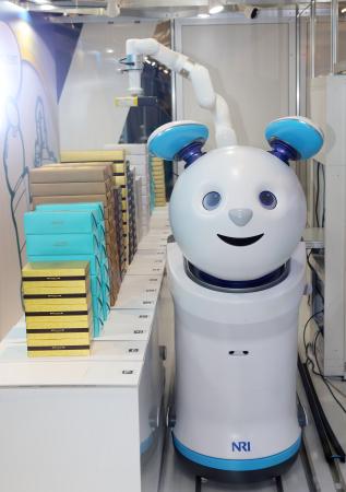 注文を受けた商品をしっぽの吸盤でつかむロボット「ピックルくん」＝１０月、成田空港