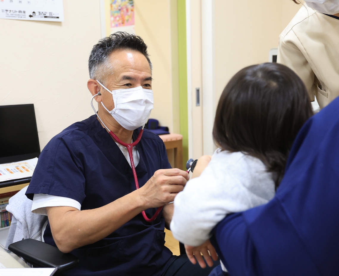来院した子どもの診察をする金谷能明院長（左）＝５日、大分市下郡東のかなや小児科