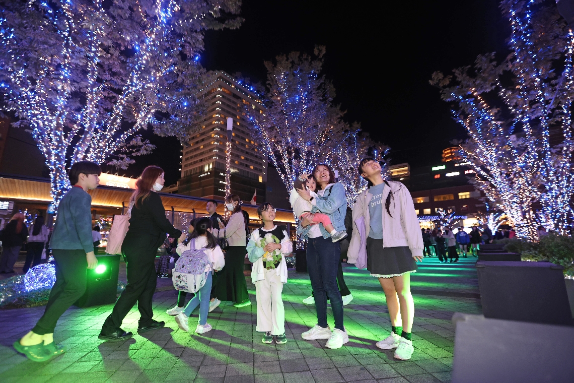 ＪＲ大分駅府内中央口広場に点灯したイルミネーションを楽しむ家族