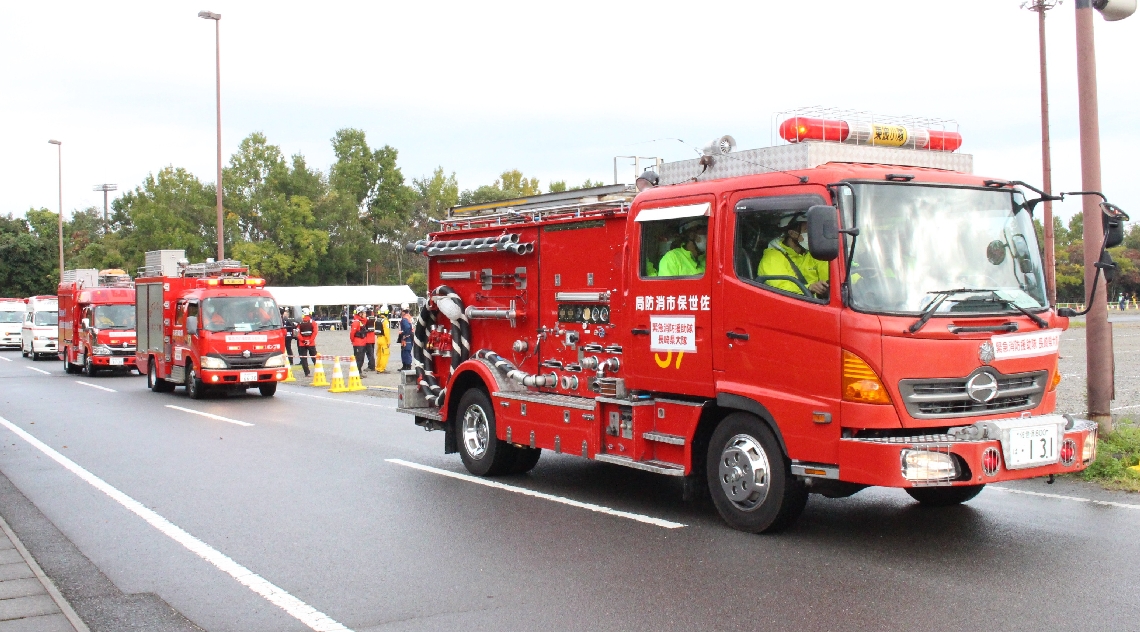 災害発生を想定した訓練で出動する緊急車両＝大分市の大分スポーツ公園