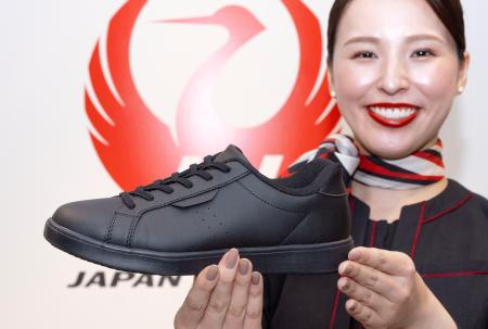 スニーカーを持つ客室乗務員＝１３日午前、東京都大田区