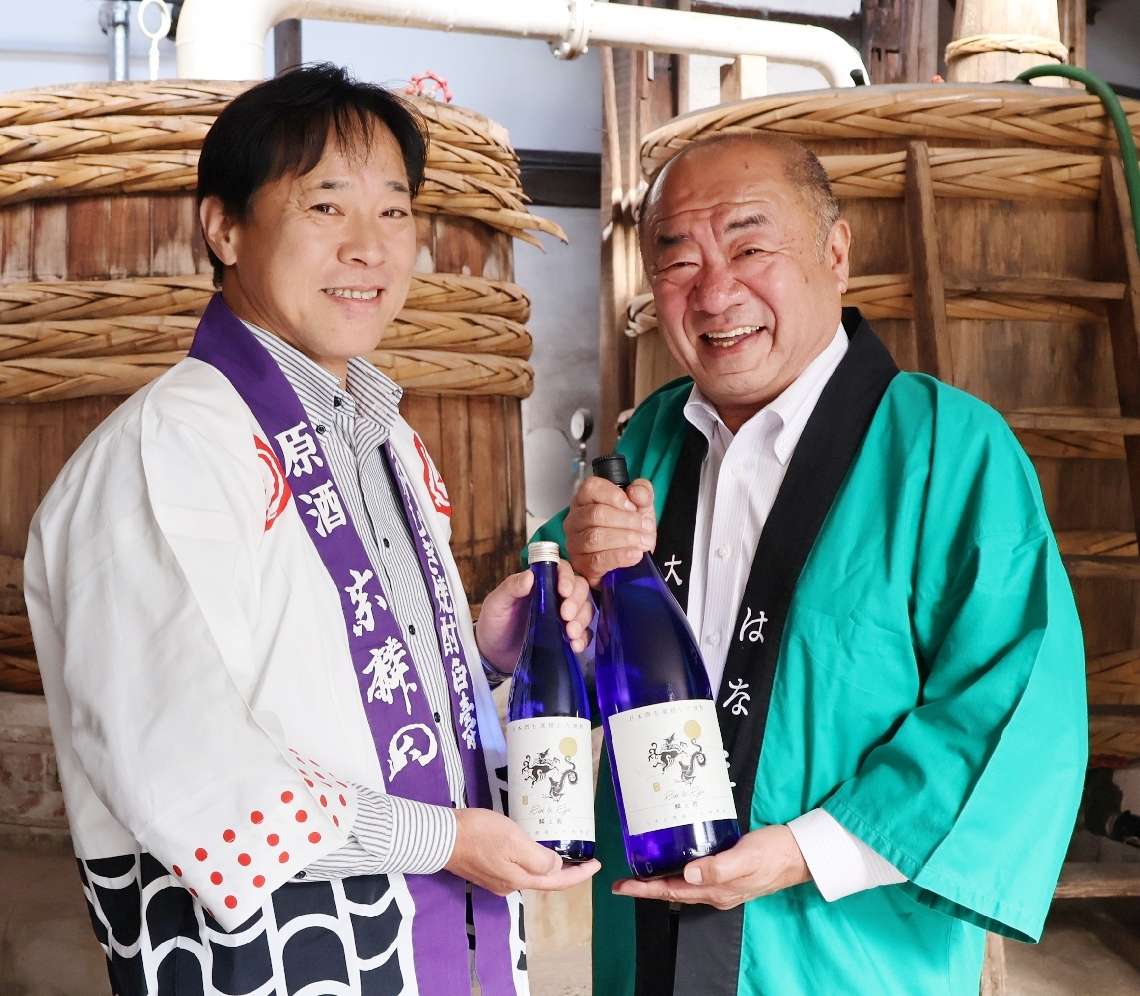 木おけ蒸留器の前でタッグ商品第２弾「麟と龍」をアピールする実崎支配人（左）と池田専務＝臼杵市臼杵の小手川酒造