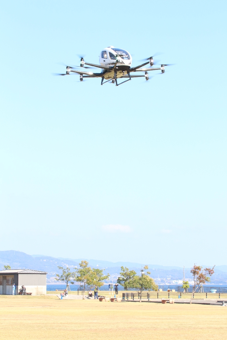 地上約３０メートルまで浮上した「空飛ぶクルマ」の有人デモフライト＝１５日、別府市の別府国際観光港多目的広場