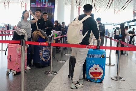 北京首都国際空港の日本便などを扱うカウンターに並ぶ人たち＝１６日（共同）