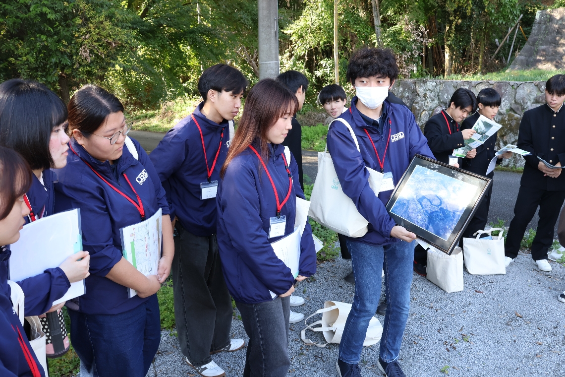 八坂川の河川改修前の写真を見る大学生たち＝杵築市本庄