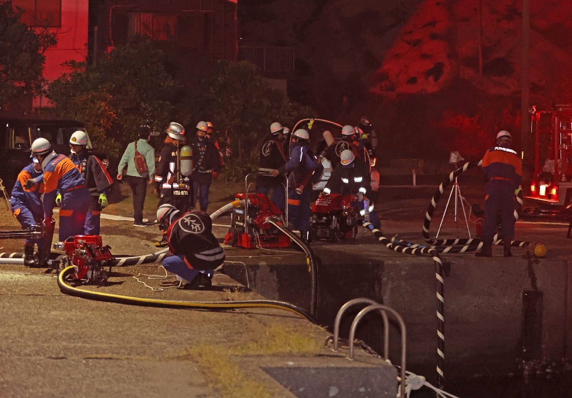 消火用水として海水をくみ上げる消防隊員ら＝１８日午後８時５７分