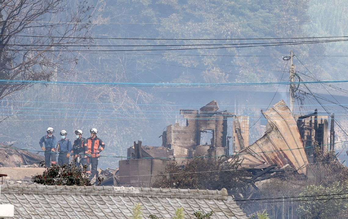 火災現場を調べる消防隊員＝１９日午後１時４１分、大分市佐賀関