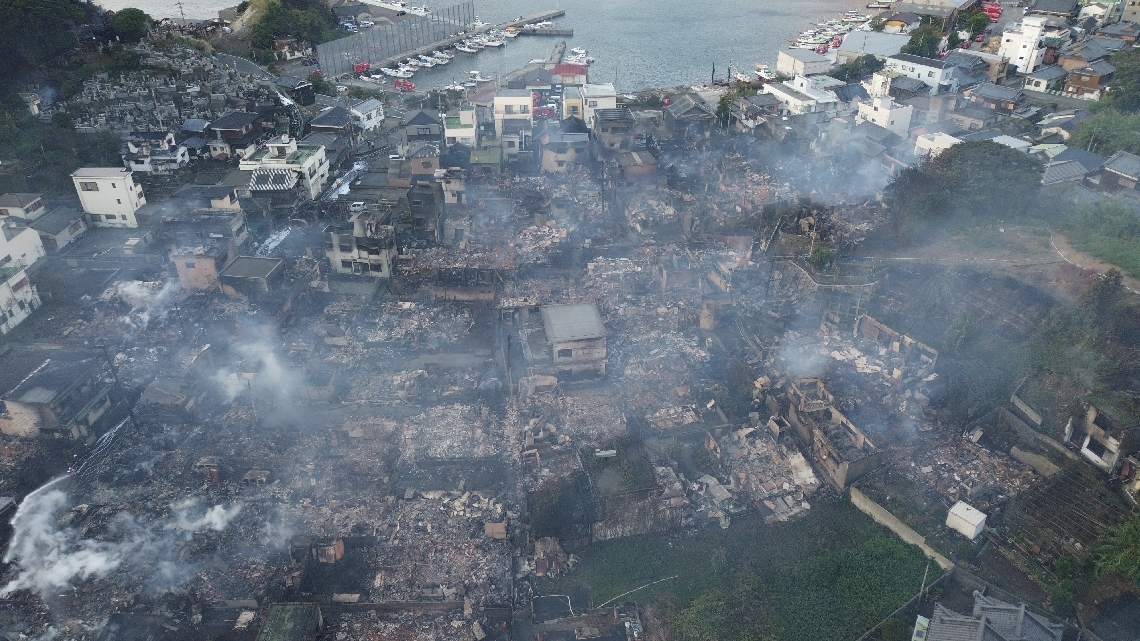一夜明け、被害状況が明らかになった集落。焼け跡に白煙が立ち込めていた＝１９日午前７時３７分（ドローンで撮影）