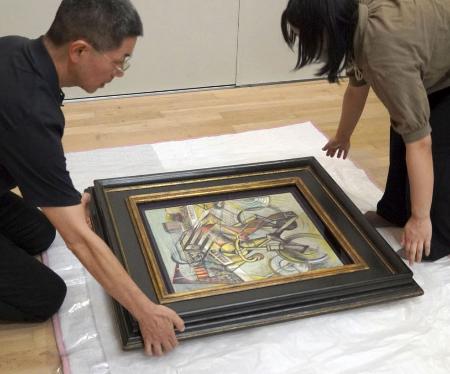 贋作と判断した油彩画「自転車乗り」を梱包する徳島県立近代美術館の学芸員＝７月、徳島市