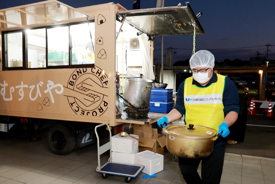 出来たての寄せ鍋を被災者の元へ運ぶコープおおいたの得松央さん＝２０日、大分市佐賀関